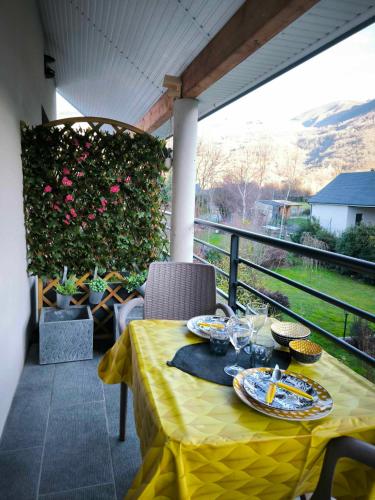 a table with a yellow table cloth on a balcony at Le balcon des cimes in Adast