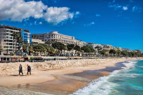 2 personnes marchant sur la plage près de l'océan dans l'établissement Cannes 1 bedroom apartment - M1, à Cannes