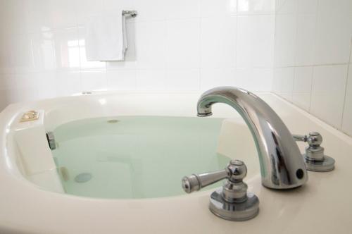 a sink with a faucet in a white bathroom at Gran Hotel De Lago - El Coca in Puerto Francisco de Orellana