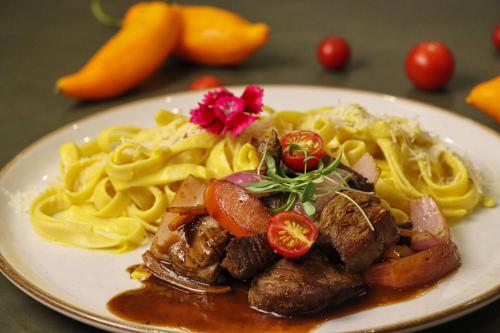 a plate of pasta with meat and vegetables on a table at Rado Hotel - Quintanas in Trujillo