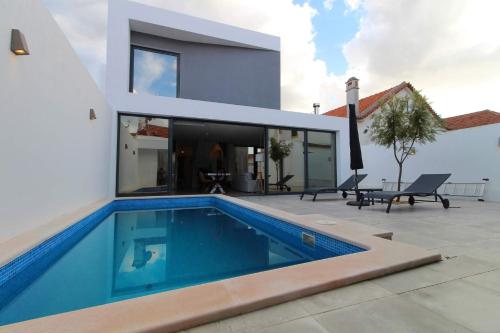 a swimming pool in front of a house at Casa Marinda T3 com Piscina in Vila Nova de Milfontes