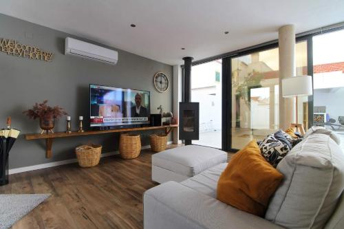 a living room with a couch and a flat screen tv at Casa Marinda T3 com Piscina in Vila Nova de Milfontes