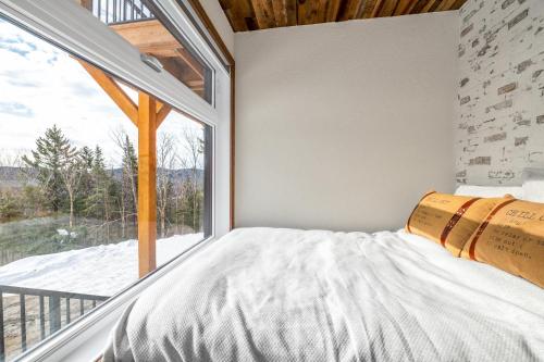a bedroom with a bed and a large window at CHAMONIX - Micro Chalet with Panoramic Mountain Views near Québec in Lac-Beauport