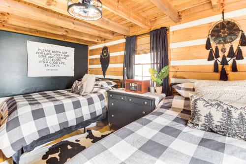 two beds in a room with wooden walls at 3 Mi to Dtwn Ellijay Tree-Lined Cabin with Deck! in Ellijay