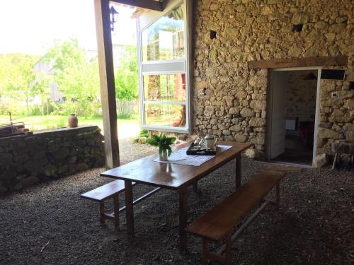 une table en bois et une fenêtre dans un bâtiment en pierre dans l'établissement gite des prés martin, à Chaille sous les Ormeaux