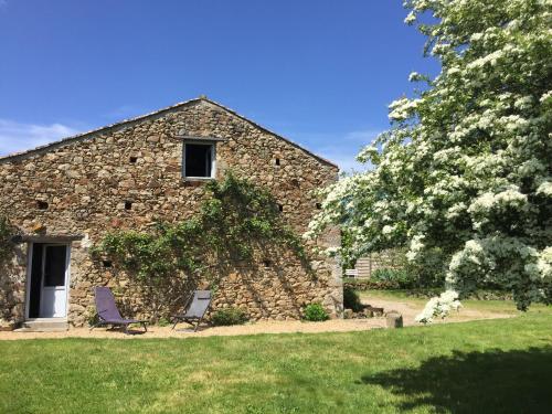 - un bâtiment en pierre avec deux chaises devant dans l'établissement gite des prés martin, à Chaille sous les Ormeaux