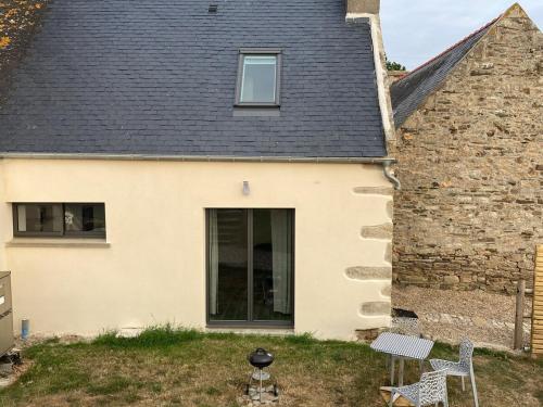 une maison blanche avec une fenêtre et un bâtiment dans l'établissement Gite sur ferme équestre, à Pouldreuzic