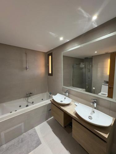 a bathroom with two sinks and a tub and a mirror at Marina Casa Del Mar - Amazing Sea & Mosque views in Casablanca