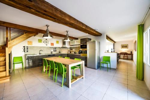une cuisine avec une table en bois et des chaises vertes dans l'établissement Saint Emilion, au milieu des vignes, à Saint-Sulpice-de-Faleyrens