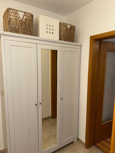 a white cabinet with a mirror and baskets on top at Cozy City Apartment Penzberg in Penzberg