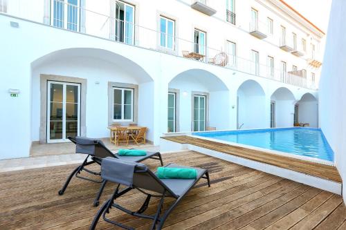 a patio with two chairs and a swimming pool at Jump Into the Lull Apartment in Faro