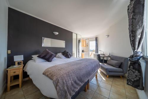 a bedroom with a large bed and a chair at Les Loges du Luberon in Coustellet