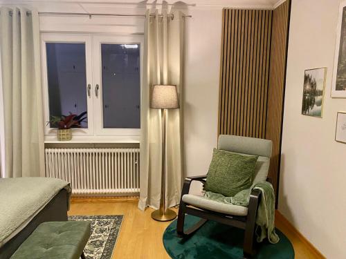 a bedroom with a chair and a lamp and a window at FoRest House in Rosenfors