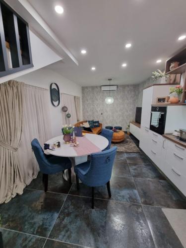 a kitchen and living room with a table and blue chairs at Vila Santa Maria Hvar with jacuzzi in Jelsa