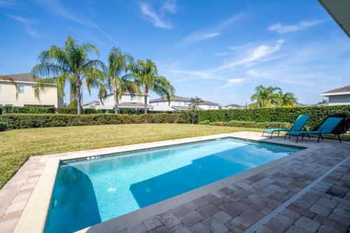 a swimming pool in a yard with two chairs at 510 BS - 5BD Cozy Family Haven with Pool in Orlando
