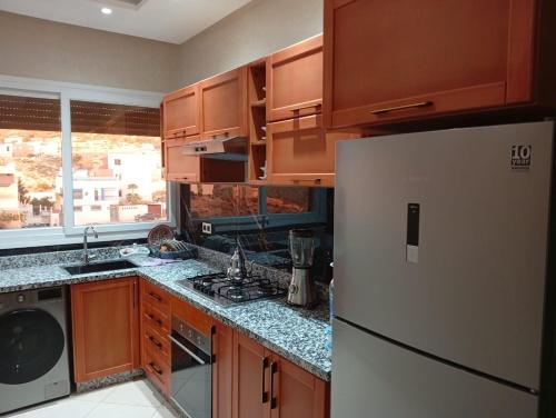 a kitchen with wooden cabinets and a white refrigerator at taghoba surf house in Tamraght Ouzdar