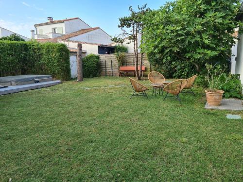 a yard with three chairs and a table in the grass at Villa de la Cible in Saint-Martin-de-Ré