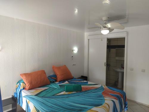 a bedroom with a bed with colorful sheets at Fare Ara Location Huahine in Fare