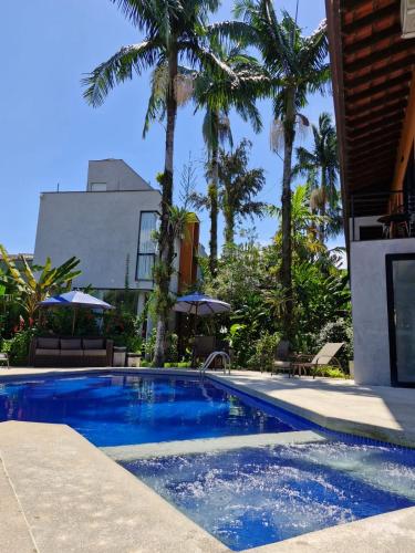 a swimming pool with palm trees and a building at Pousada Armação de Camburi in Camburi