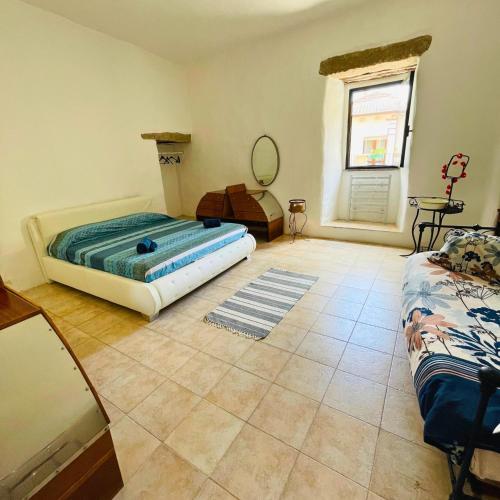 a bedroom with a bed and a mirror and a window at Rifugio Antico nella Città di Pietra in Tempio Pausania