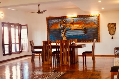 ein Esszimmer mit einem Tisch und einem Gemälde an der Wand in der Unterkunft Kesaviyam Unique Ocean View Luxury Suites vicinity Kovalam Light house in Kovalam