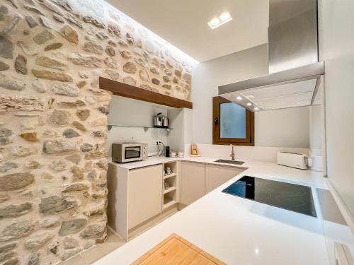a kitchen with white counters and a stone wall at Can Bona Casa - Apartamento con vistas a la plaza in Besalú