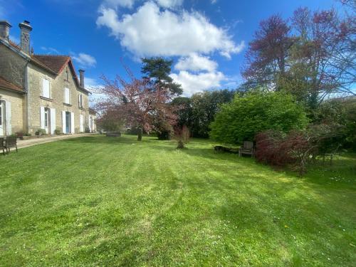 une cour herbeuse avec une maison et un banc dans l'établissement La Montgrande Bed & Breakfast, à Aulnay