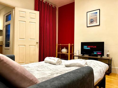 a bedroom with a bed and a tv and red curtains at Last-Minute Reserve l Exclusive Deal l Sleeps Up to 5 l Free Parking l cottage l close to city in Birmingham