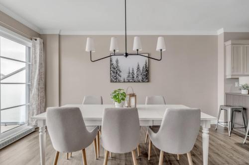 a white dining room with a white table and chairs at Initial / Natur / Chutes-Montmorency in Boischâtel