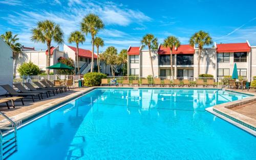 a swimming pool with chairs and palm trees at Dans Florida Condos Sea Life at Runaway Bay in Bradenton Beach