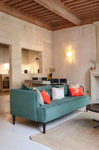 un salon avec un canapé vert avec des coussins colorés dans l'établissement Appartement de Caractère avec Cachet Unique à Uzès, à Uzès