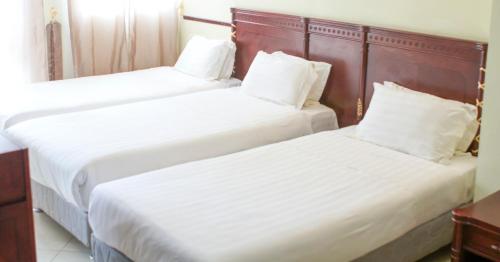two beds in a hotel room with white sheets at AG Hotel Gondar in Gonder