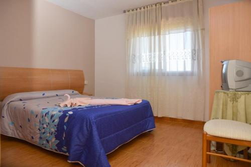- une chambre avec un lit doté d'une couverture bleue et d'une télévision dans l'établissement Jumboli, à Redondela