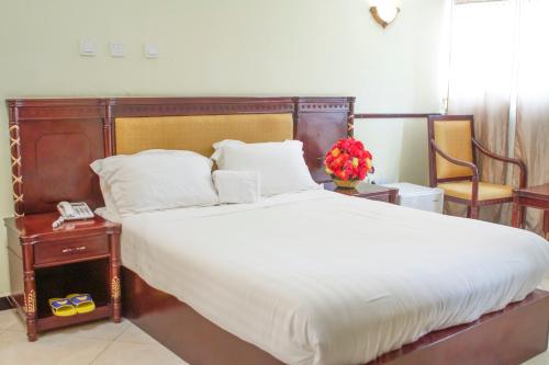 Schlafzimmer mit einem großen Bett mit einem Kopfteil aus Holz in der Unterkunft AG Hotel Gondar in Gonder