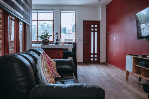 a living room with a leather couch and a kitchen at Casa FRANLUS Apartmento 3 Planta alta in San Cristóbal de Las Casas