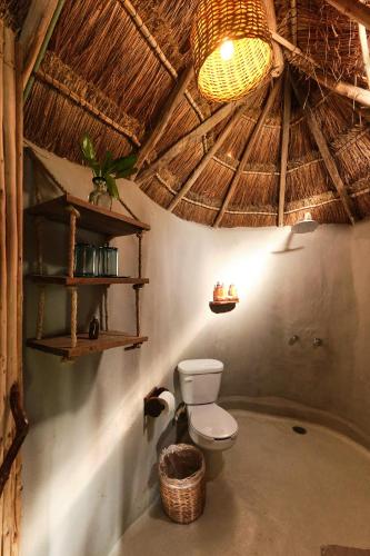 a bathroom with a toilet and a straw roof at Art Village Tulum in Tulum