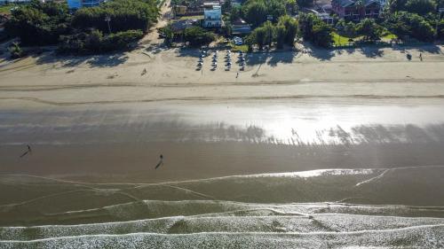 an aerial view of a beach with people walking on the sand at Pousada Conca di Mare - Restaurante - Pé na areia in Bertioga