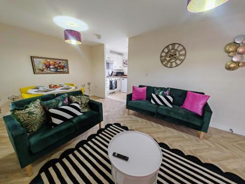 a living room with two green couches and a table at Dakota 2Bed - AwayOnBusiness in Eastleigh