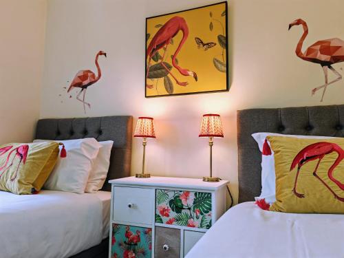 a bedroom with two beds and two lamps and birds on the wall at Dakota 2Bed - AwayOnBusiness in Eastleigh