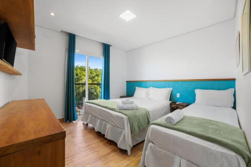a bedroom with two beds and a large window at Pousada Conca di Mare - Restaurante - Pé na areia in Bertioga