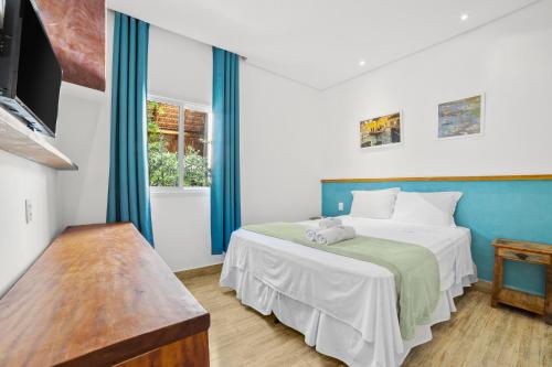 a bedroom with a large white bed with blue curtains at Pousada Conca di Mare - Restaurante - Pé na areia in Bertioga