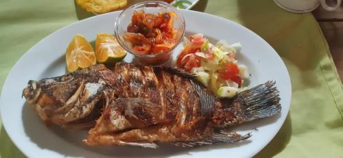 a plate of food with meat and vegetables and fruit at Hostal La Cascada San Ramón in Mérida