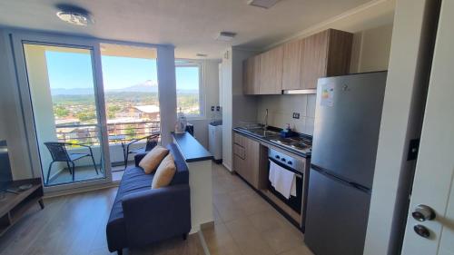 Departamento Mirador al Volcan في فيلاريكا: مطبخ مع أريكة زرقاء ونافذة كبيرة