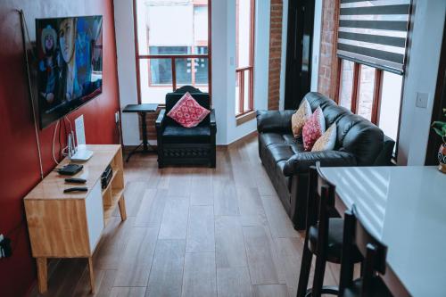 a living room with a leather couch and a television at Casa FRANLUS Apartmento 3 Planta alta in San Cristóbal de Las Casas