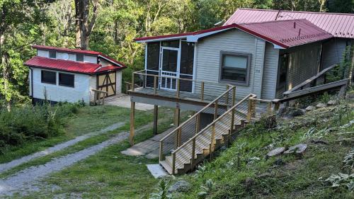 a house with a porch and a staircase leading to it at Red Roof mountain cabin with Starlink internet! in Pine Grove