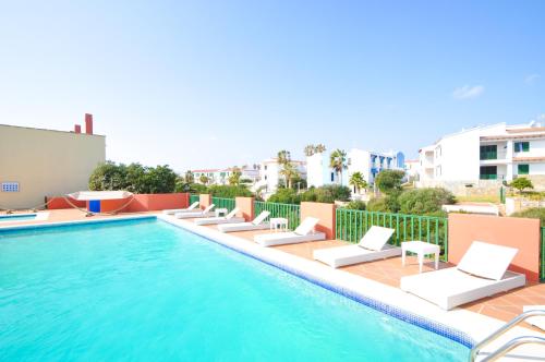 a swimming pool with chaise lounge chairs next to a building at Sant Joan Apartaments - Adults Only in Cala en Blanes