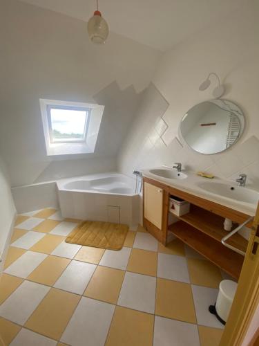 une salle de bain avec une baignoire, un lavabo et un miroir dans l'établissement Maison de charme proche océan, à Lauzach