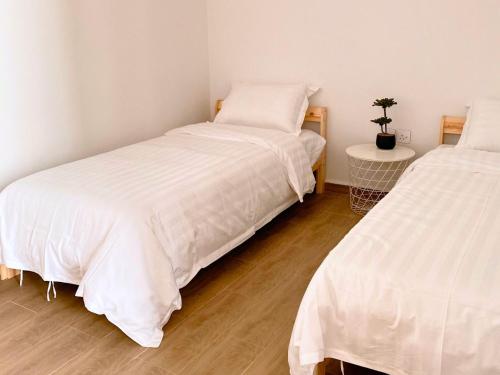 two beds with white sheets in a room at شاليه فندقي غرفتين نوم مسبح وبانيو in Banī Ma‘n