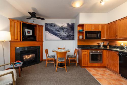a kitchen with a fireplace and a table and chairs at Village Penthouse w Views Pool and Hot Tub in Whistler