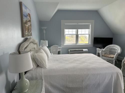 a bedroom with a white bed and a window at Sands Of Time Motor Inn & Harbor House in Woods Hole